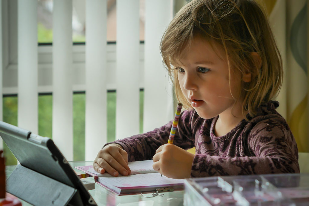 Bambina davanti al tablet mentre fa i compitini